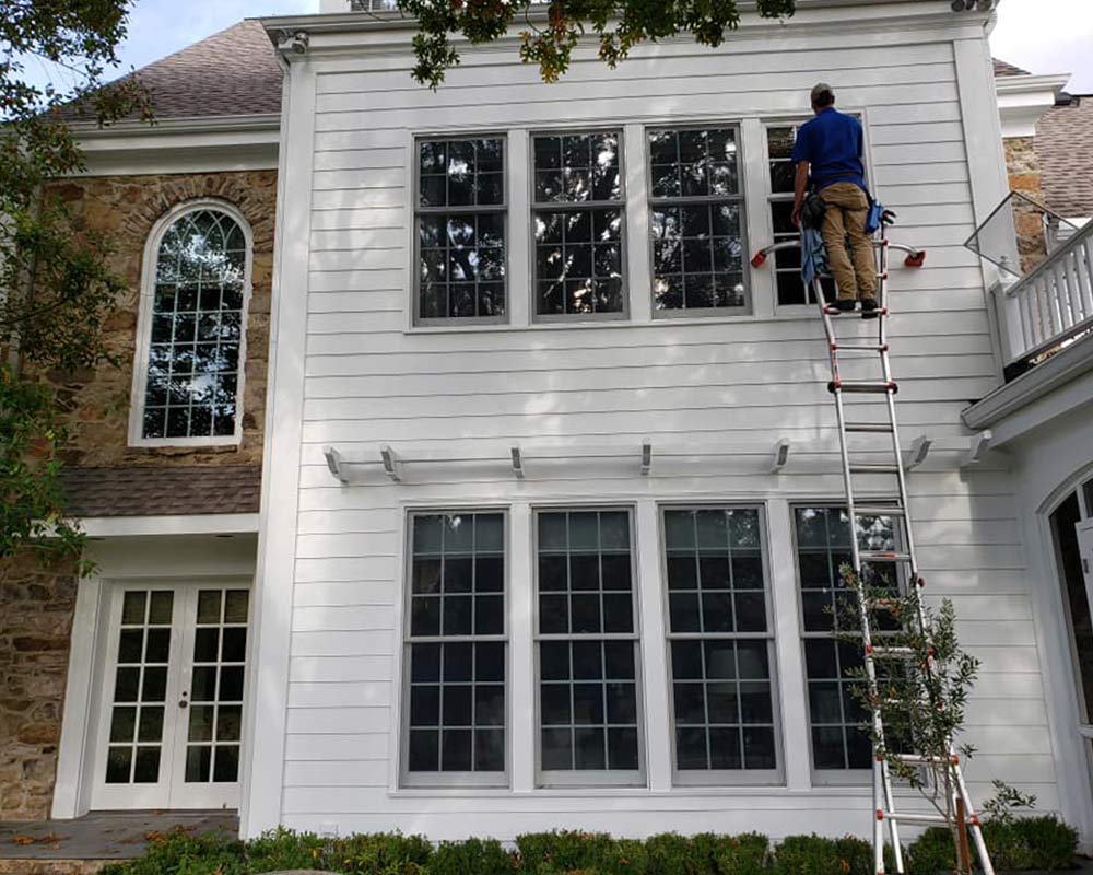 professional window cleaner on ladder cleaning home windows dallas tx